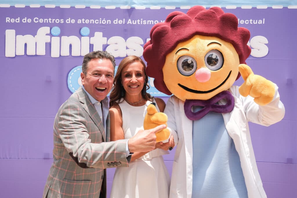 Pablo Lemus Navarro y una mujer sonriente posan junto a una mascota de un centro de atención para el autismo en Tepatitlán.