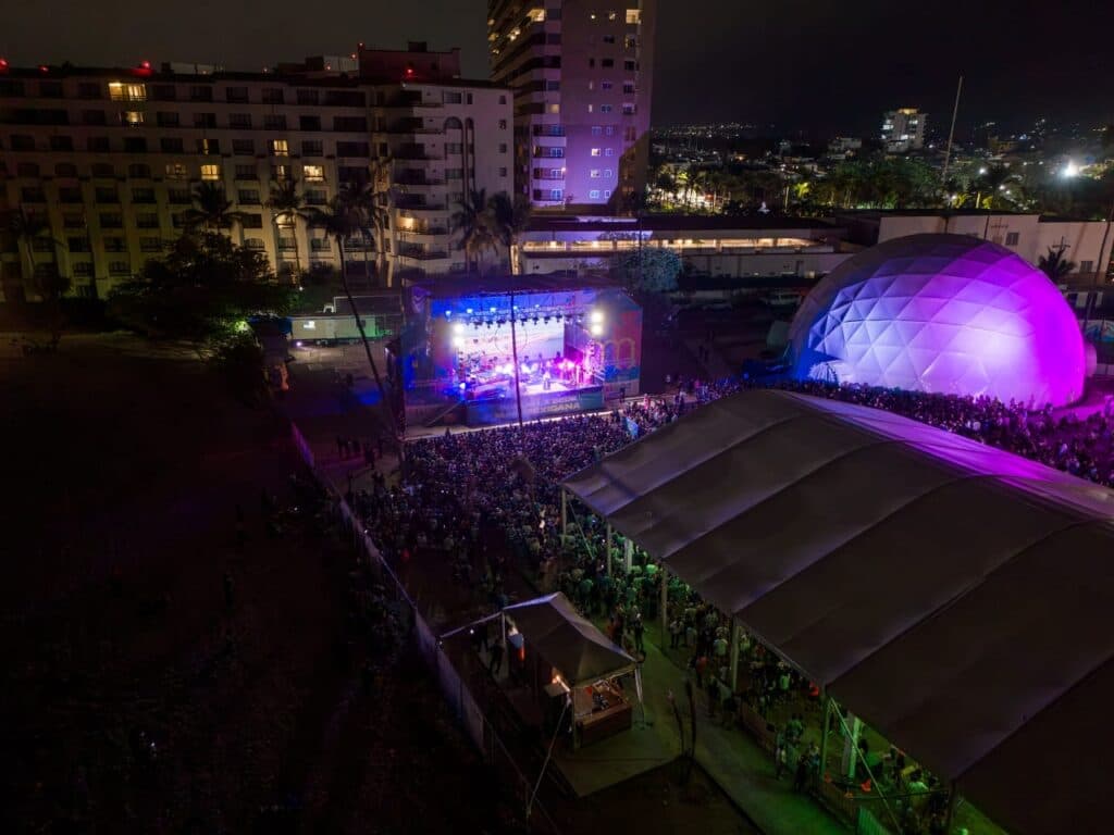 Gran concierto al aire libre en Jalisco, con un público numeroso disfrutando de la música bajo luces coloridas durante el Mundial.