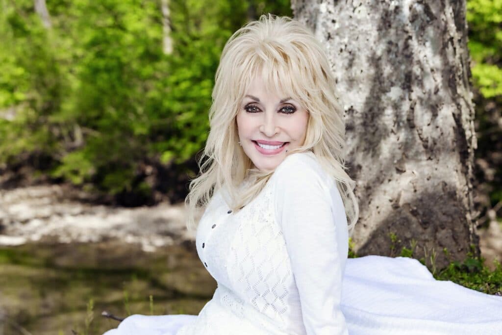 Dolly Parton sonríe en un entorno natural, recordada como una icónica figura de la música country tras su fallecimiento.