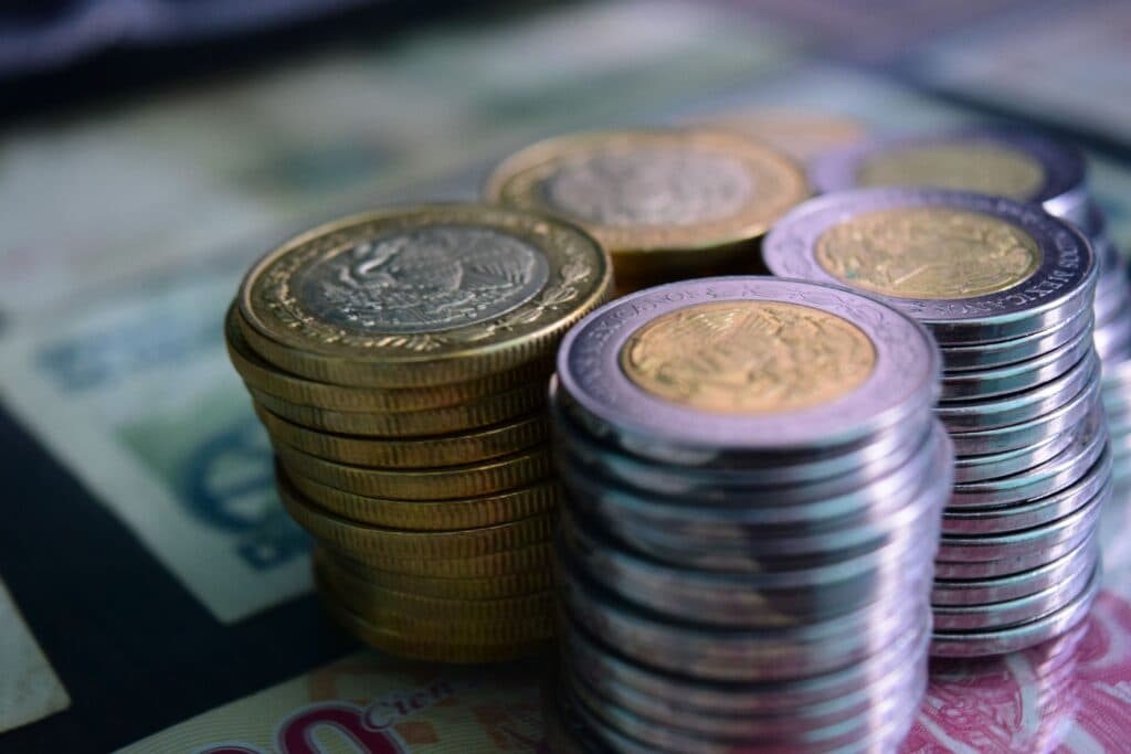 Monedas y billetes mexicanos apilados, representando el contexto económico y la inflación en México.