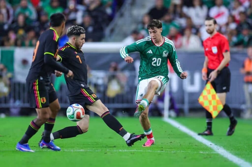 Jugadores de la Selección Mexicana y Perú compiten por el balón en un partido amistoso, destacando la acción y la intensidad del juego.