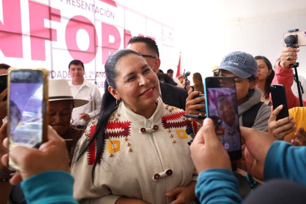 Ana Lilia Rivera sonríe mientras es rodeada por simpatizantes que la graban con sus teléfonos en un evento político en Tlaxcala.