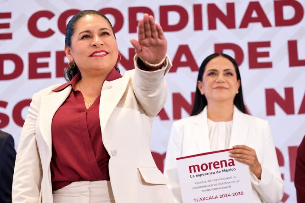 Ana Lilia Rivera, nueva Coordinadora de Defensa de MORENA en Tlaxcala, gesticula durante su presentación junto a otra funcionaria.
