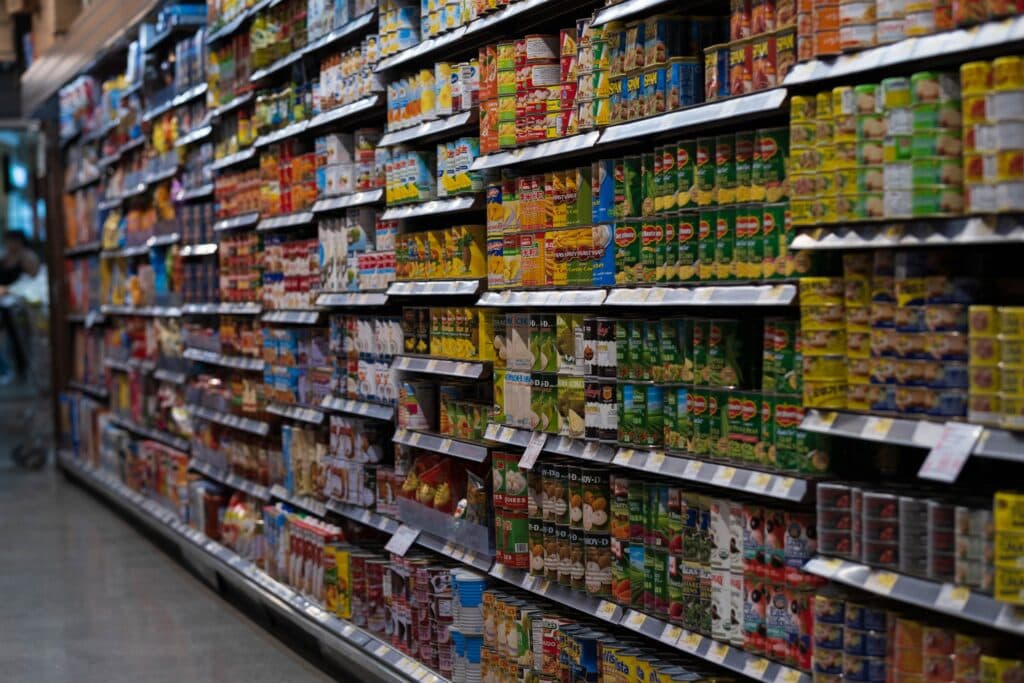 Estantes de supermercado repletos de productos enlatados y bebidas, reflejando el impacto de los nuevos impuestos propuestos.
