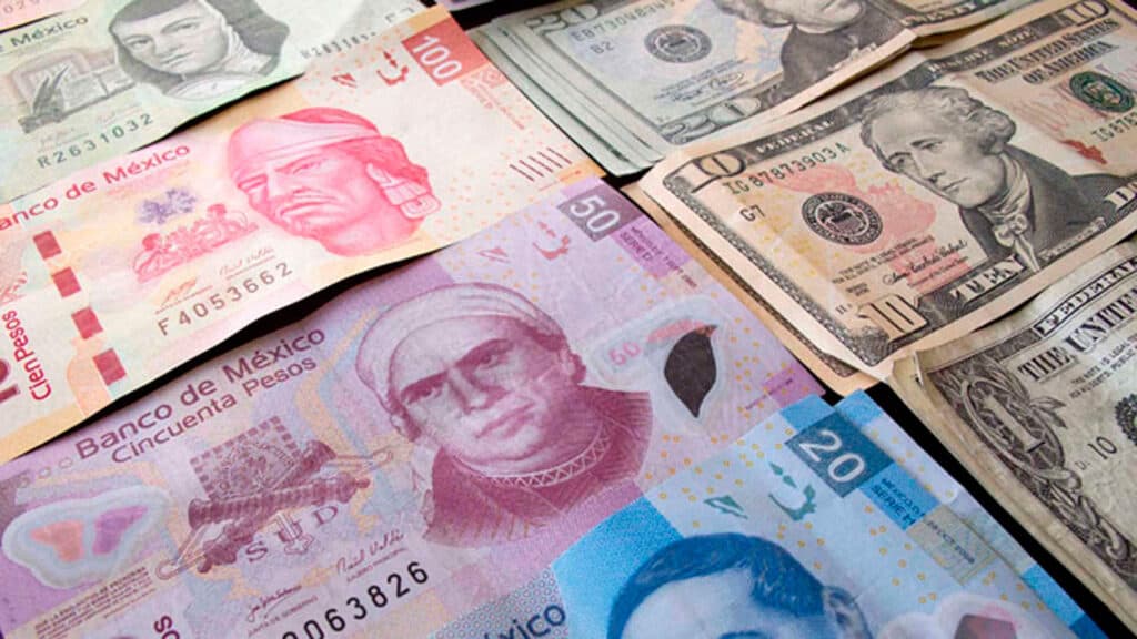 Billetes de pesos mexicanos y dólares estadounidenses sobre una superficie, ilustrando la fluctuación del tipo de cambio.