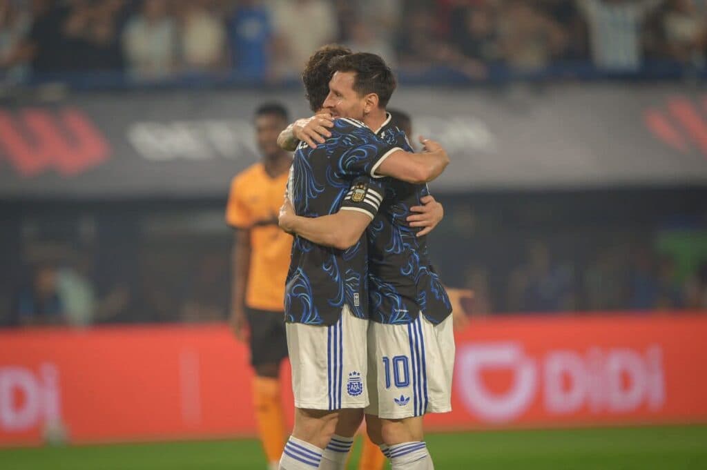 Lionel Messi y un compañero se abrazan en un partido, luciendo la camiseta de la Selección Argentina, en un ambiente de celebración.