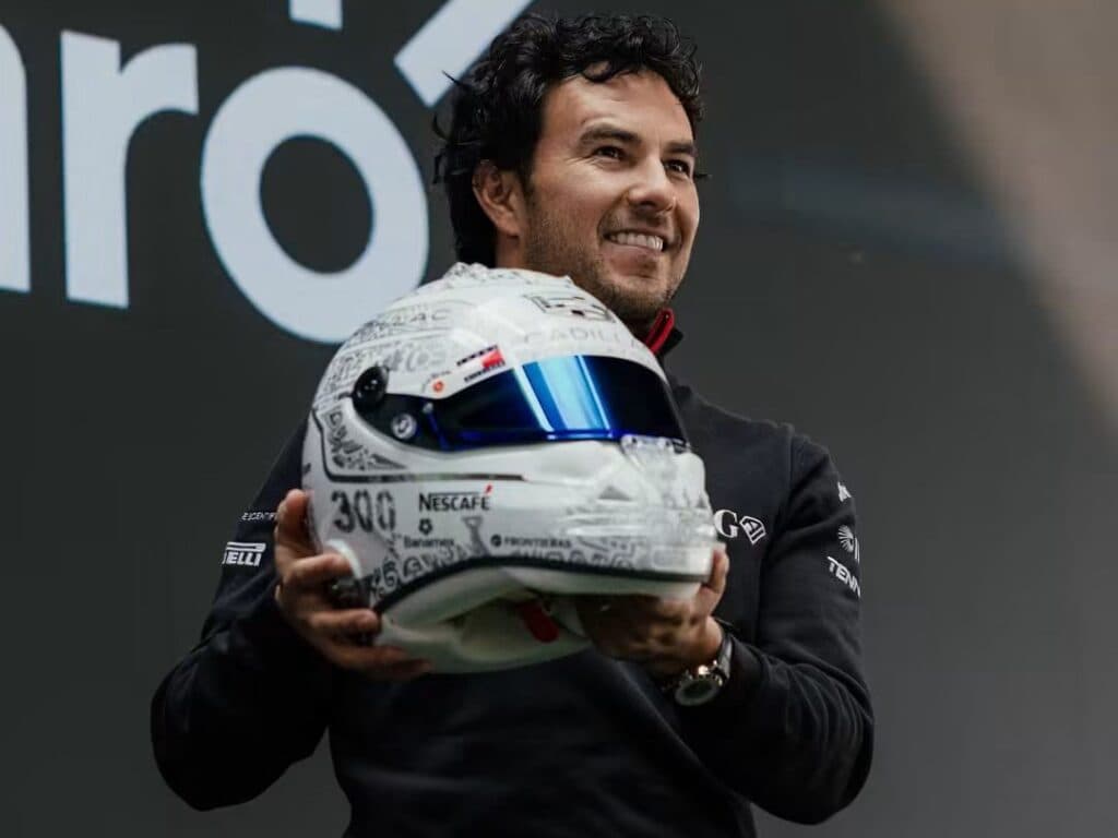 Sergio Checo Pérez sostiene su casco especial para el GP de México 2026, decorado con símbolos mexicanos y el número 300.