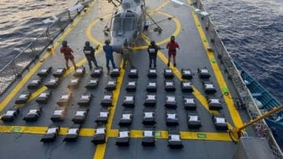 Seis personas detenidas en un barco de la Secretaría de Marina, rodeadas de paquetes de cocaína decomisados en Oaxaca.