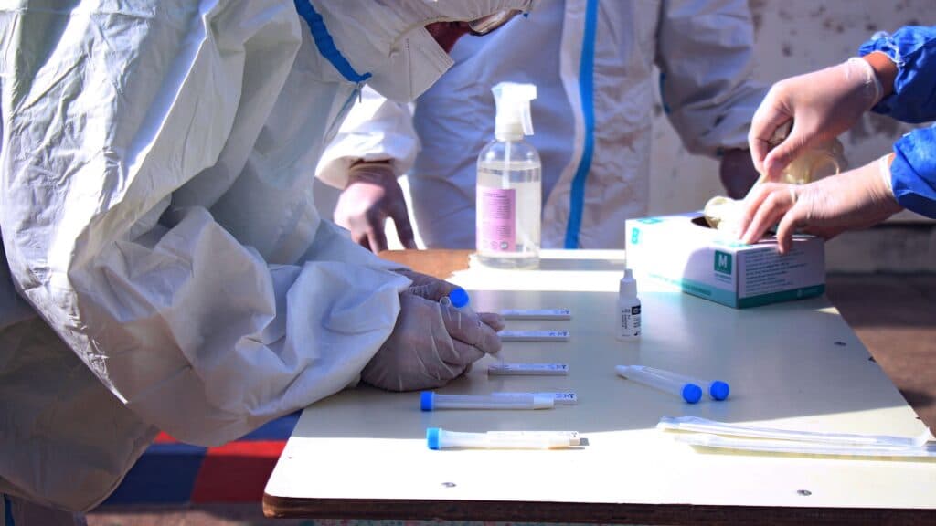 Investigadores en trajes de bioseguridad manipulan muestras de laboratorio en un entorno controlado, relacionado con estudios de peste.